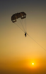 Parasailing extreme sports on beach in sunset background. Paragliding in front of an amazing sunset. A beautiful background of a parasailing parachute on the backdrop a sunset on an evening sky.
