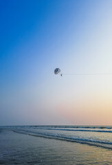 Parasailing extreme sports on beach in blue sky background. Man is parasailing in the blue sky. Paragliding in the clear sky above the sea.