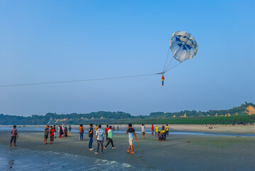 Parasailing extreme sports on beach in blue sky background. Man is parasailing in the blue sky. Paragliding in the clear sky above the sea.