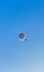 Parasailing extreme sports on beach in blue sky background. Man is parasailing in the blue sky. Paragliding in the clear sky above the sea.