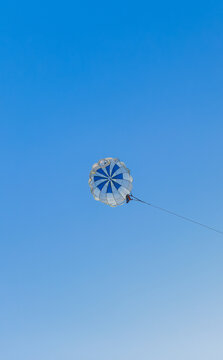 Parasailing extreme sports on beach in blue sky background. Man is parasailing in the blue sky. Paragliding in the clear sky above the sea.