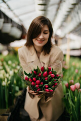 Model with a bouquet in a greenhouse of flowers
