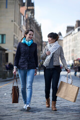 Two happy women shopping together, having fun and laughing