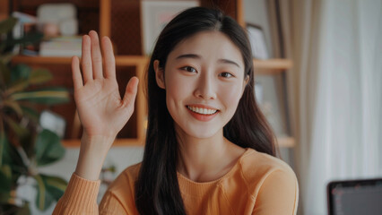 Young woman waves hello during a friendly virtual meeting from home.