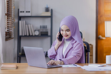 Asian islamic women working planning and data analysis financial with smartphone and laptop at office desk, Business accounting and marketing online concept.