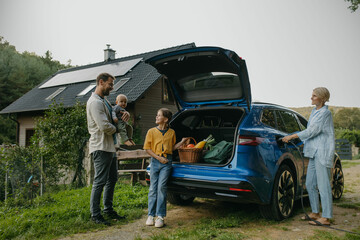 Family with electric car in front house with solar panels on roof. Solar, green energy and...