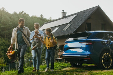 Family with electric car in front house with solar panels on roof. Solar, green energy and...