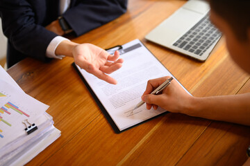 Close up of unrecognizable man signing a contract with insurance agent