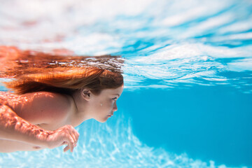 Kids holidays and summer vacation concept. Child swimming underwater in swimming pool. Funny kids...