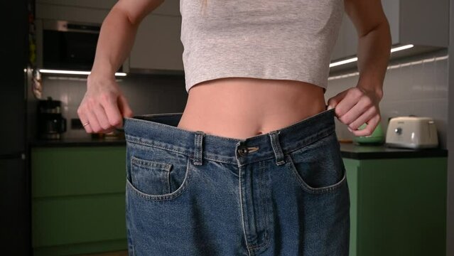 Close up female slim abdominal waist dieting sport workout healthy lifestyle. Unrecognizable girl woman shows weight loss wearing old jeans big size fitness sports gym body slimming