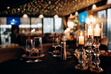 On the festive table in the area of the wedding banquet, candles are placed in candlesticks of a...