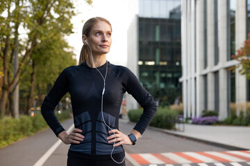 A fitness-focused woman pauses during her run in the city, displaying determination and confidence....