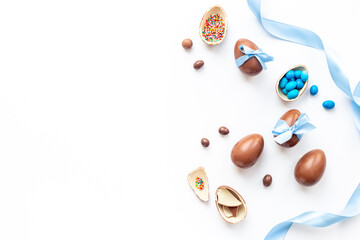 Easter festive background. Chocolate Easter eggs in blue ribbon with sweets