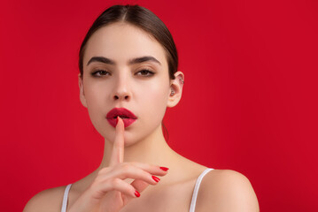 Shh, keep silence. Woman gesturing hush sign, on studio background. Finger on lips, silent gesture,...