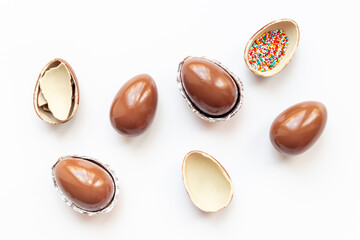 Chocolate eggs broken on white background. Chocolate sweets, top view