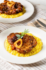 Ossobuco meat, specialty of Lombard cuisine of cross-cut beef shanks braised with onion, white wine, and broth. Served with risotto alla milanese, rise made with saffron. Italian dish. Vertical.