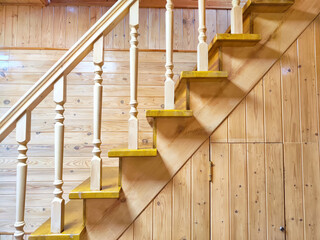 A pine wooden staircase with white balusters in a cozy home. Wooden Staircase in a Rustic Interior Setting