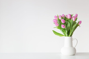 pink tulips in white jug on white background