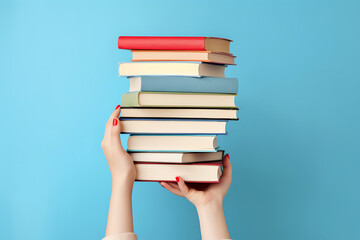 Woman hands holding pile of books over light blue background. Education, library, science, knowledge, studies, book swap, hobby, relax time