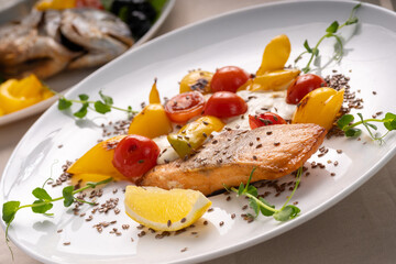 Baked salmon served with tomatoes grill, lemon and microgreen