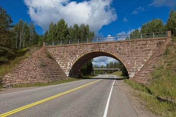 Fototapeta na wymiar Old arch bridge made of stone over Turuntie road in summer, Myllylampi, Nummela, Finland.