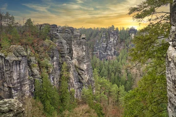 Washable wall murals Bastei Bridge Rugged rocks at Basteibridge at sunset. Wide view over trees and mountains