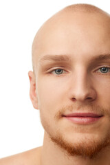 Close-up portrait of handsome young bald man with unshaved face, blue eyes, clear spotless skin isolated on white studio background. Concept of skin care, male beauty and cosmetics, youth, self-care