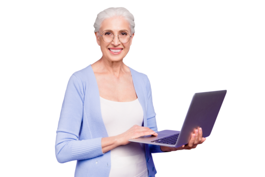 Grey haired old nice beautiful cheerful smiling woman wearing spectacles holding laptop learning online course. Isolated over violet purple background