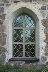 Grey painted wood framed window with arch on a stone building.