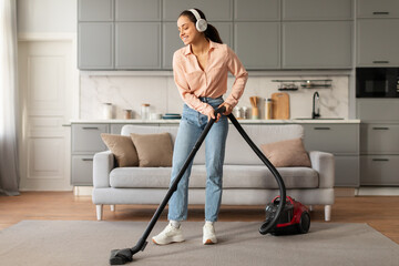 Content woman vacuuming with headphones in neat room
