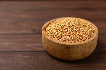 Green buckwheat in a bowl on a wooden kitchen table.Superfood.Raw buckwheat porridge.Healthy vegan food concept, eco products, diet. Copy space.Organic food.weight loss and proper nutrition.