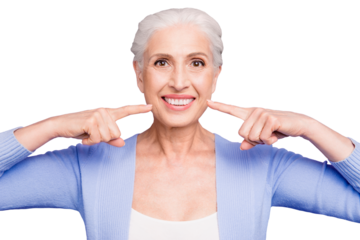Concept of having strong healthy white perfect teeth at old age. Portrait of old lady with beaming smile pointing on her teeth, isolated over violet background
