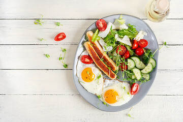 Keto breakfast. Fried eggs and chicken sausage and fresh salad. Top view, flat lay