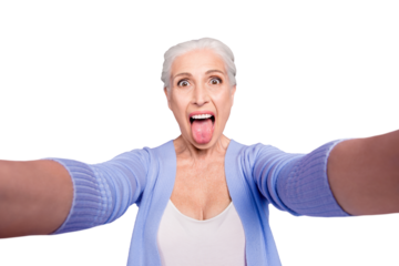 Self portrait of gray haired beautiful smiling funky funny playful old lady wearing casual, grimacing, showing tongue out, isolated over violet background