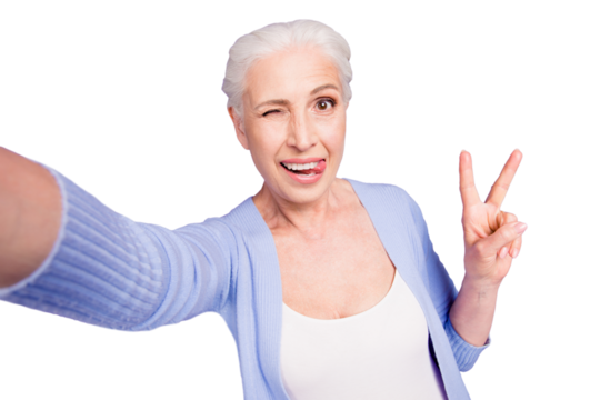Self portrait of gray haired old nice beautiful cheerful funny smiling woman showing v-sign gesture, tongue out, winking. Isolated over violet purple background