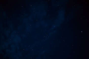 Stars in the night sky through the clouds. Beautiful starry night sky with clouds.