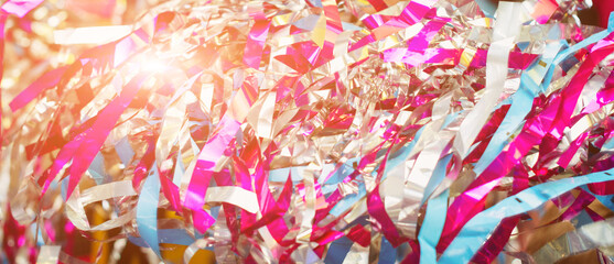 Colorful confetti and streamer lying on floor in fron of background. Festive background of confetti. Blurred glittered background