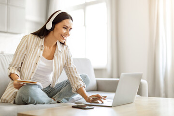 Obraz premium Online Education. Smiling Woman In Wireless Headphones Studying With Laptop At Home