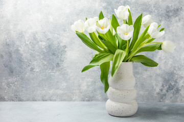 Bouquet of white tulips on a light textured background. Festive bouquet Mothers day, Valentines Day, Birthday celebration concept. Greeting card. Copy space. Place for text.