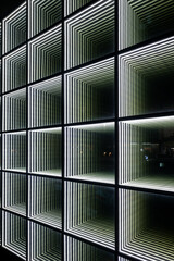 Abstract image of symmetrical green and white light patterns on a building's facade at night