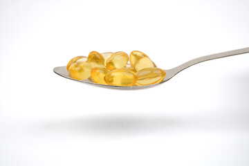 Spoon full of cod liver oil supplement capsules concept background