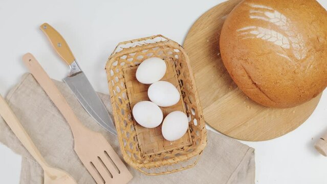 Fresh whole grain bread on kitchen table eggs and equipment for bakery cooking, free space for text or logo