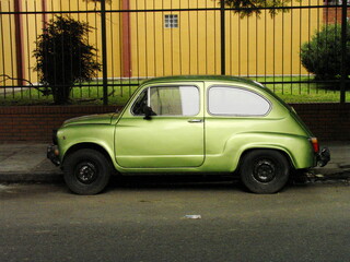 An abandoned green Fiat parked in front of a building in Buenos Aires, Argentina