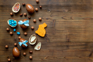 Chocolate Easter eggs in blue ribbon and bunny cookies on wooden background