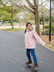 冬の公園でキャスターボードを遊んでいる小学生の女の子の様子