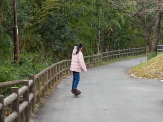 冬の公園でキャスターボードを遊んでいる小学生の女の子の様子