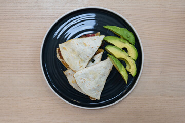 A plate of quesadilla with avocado.