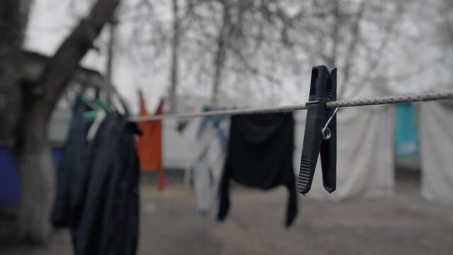 The wind sways a clothespin on a clothesline against the backdrop of drying washed clothes. The backyard of a country house.