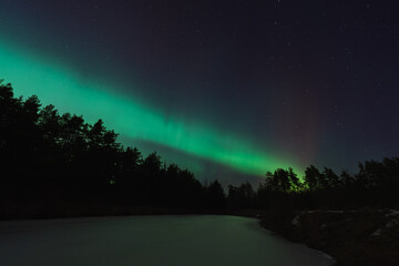 Night scene. Landscape astrophoto with northern lights in winter in the forest of Estonia.