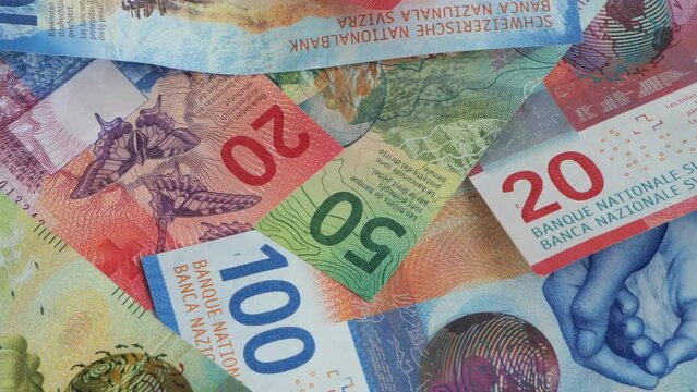 Swiss franc or francs banknotes on a table. Panning close up shot of 100, 50 and 20 franc bills, top view, no people